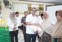 Bupati Sirajudin Lasena menyerahkan secara simbolis komoditas pasar murah kepada warga yang membeli bahan pokok dengan harga terjangkau.